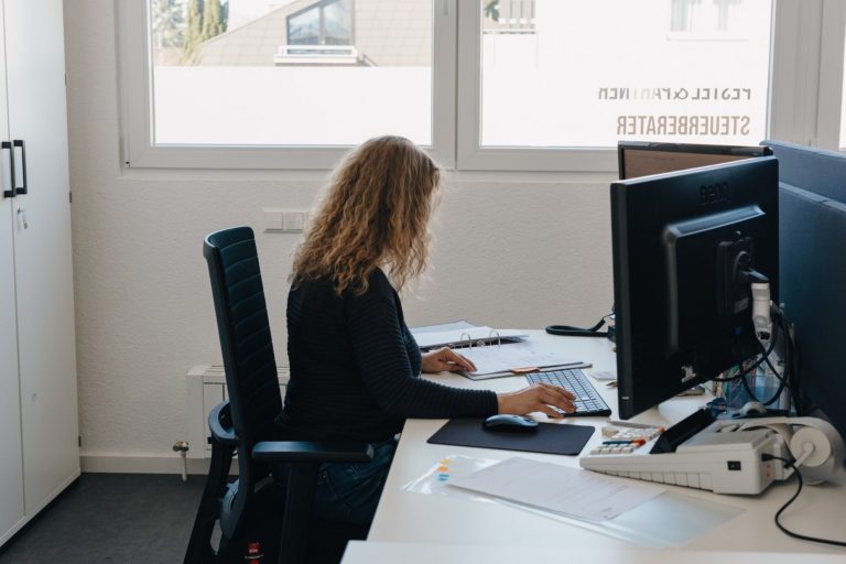 Buchhaltung Eine Person sitzt an einem Schreibtisch und arbeitet konzentriert am Computer, um die Buchhaltung durchzuführen.