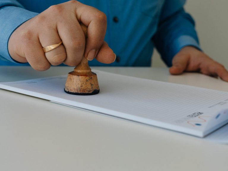 Testamentsvollstreckung Hand stempelt mit einem Dienstsiegel ein Dokument auf einem Tisch.